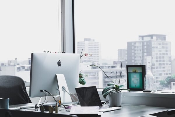 Sunlit city-view desk with iMac and orchid