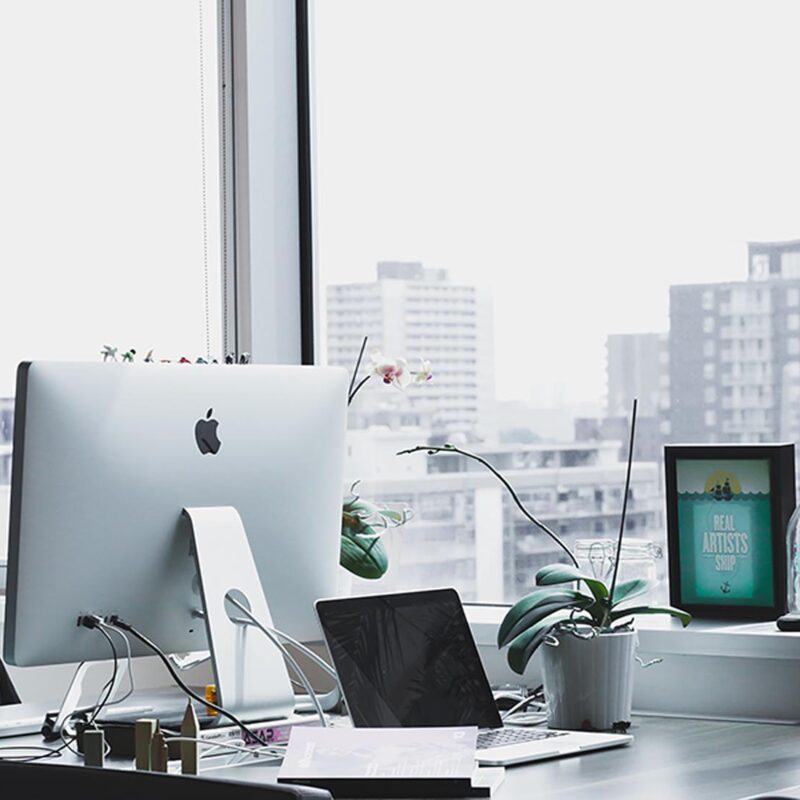 Sunlit city-view desk with iMac and orchid