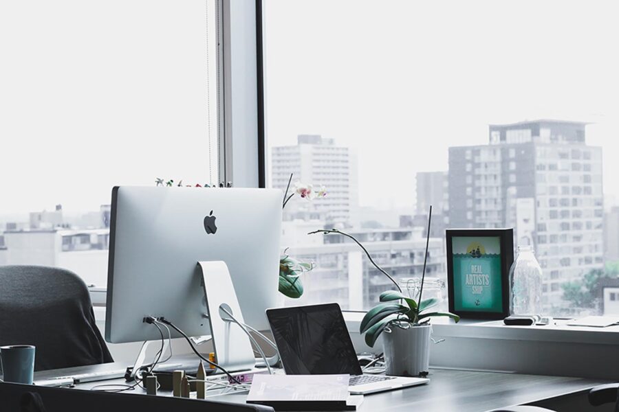 Sunlit city-view desk with iMac and orchid