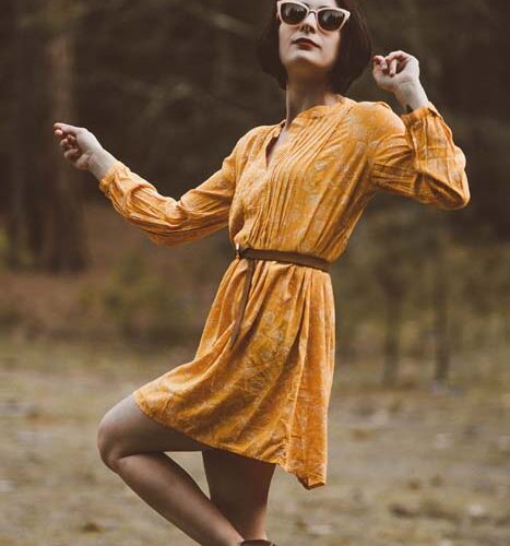Woman in yellow dress, sunglasses, outdoors.
