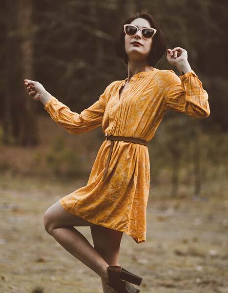 Woman in yellow dress, sunglasses, outdoors.