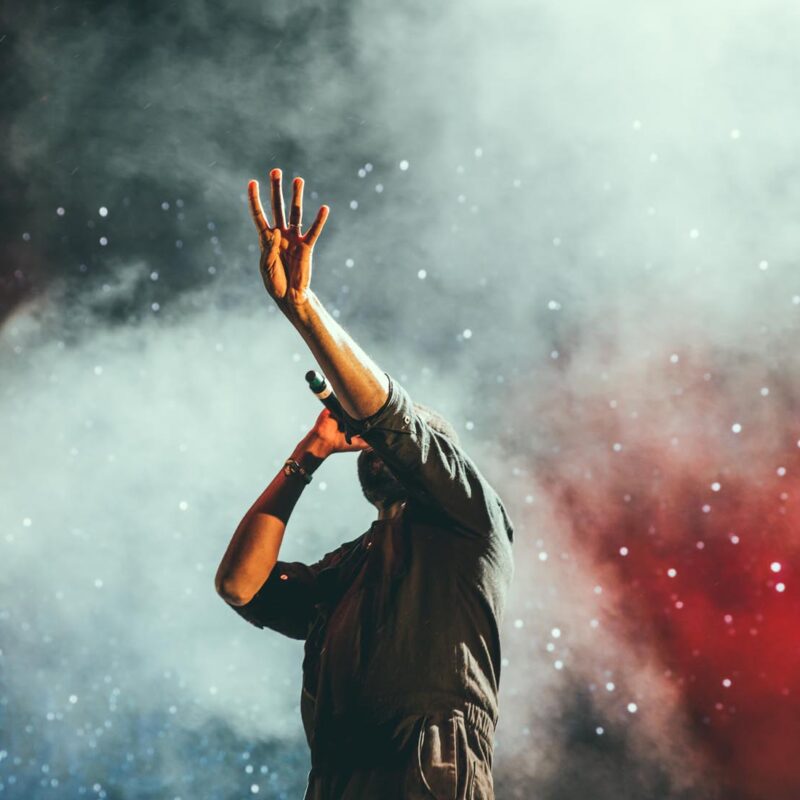 Singer performing on smoky stage with raised hand