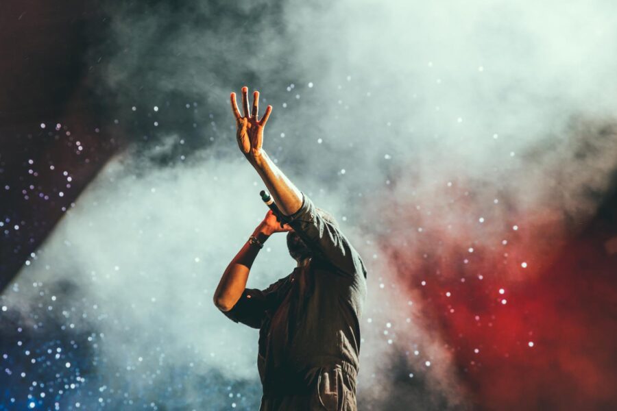 Singer performing on smoky stage with raised hand