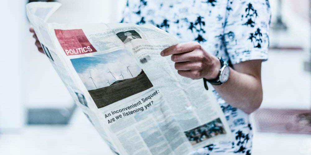 Person reading newspaper; politics section.