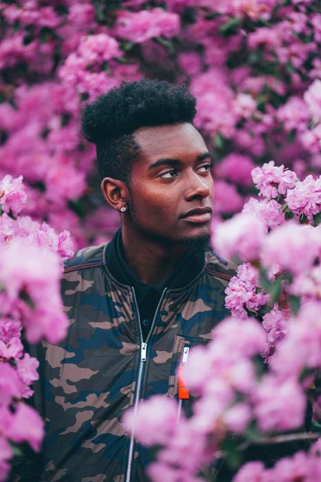 Man in camo jacket amidst pink flowers.