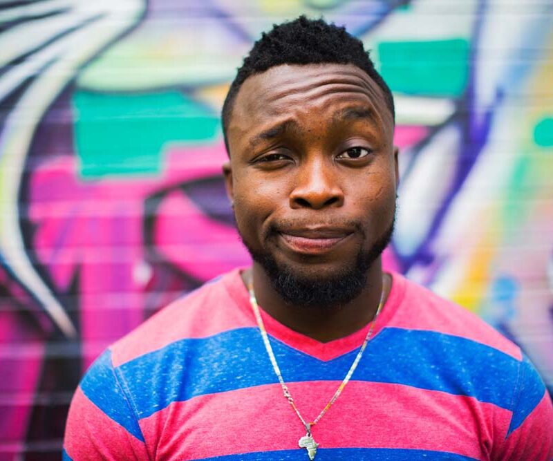 Man with amused expression in front of graffiti.