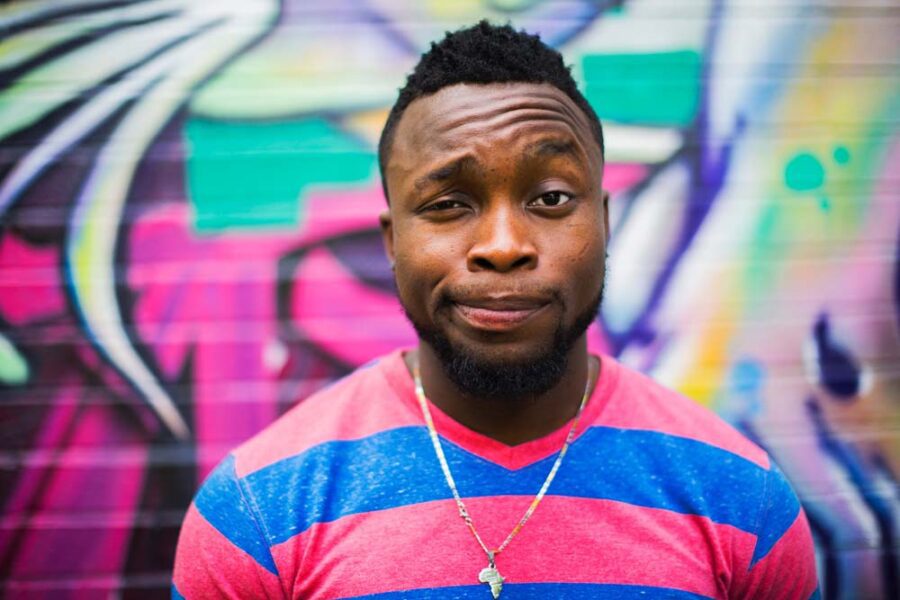 Man with amused expression in front of graffiti.