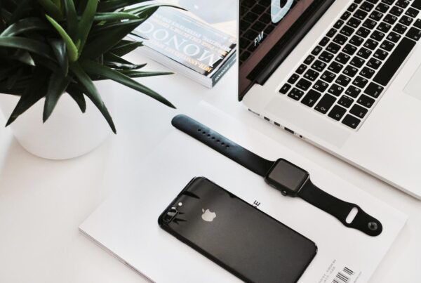 Laptop, phone, watch, and plant on desk.