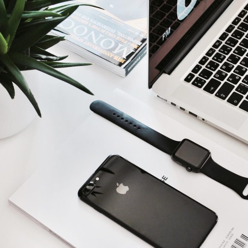 Laptop, phone, watch, and plant on desk.