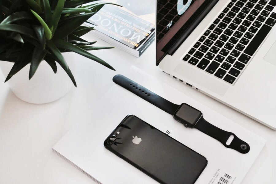Laptop, phone, watch, and plant on desk.