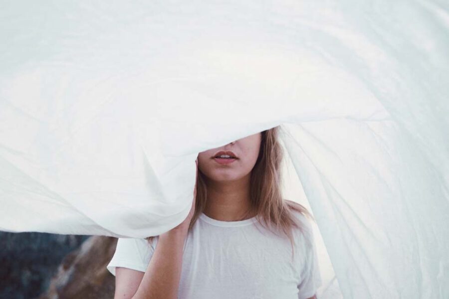 Woman's face partially hidden by white cloth.