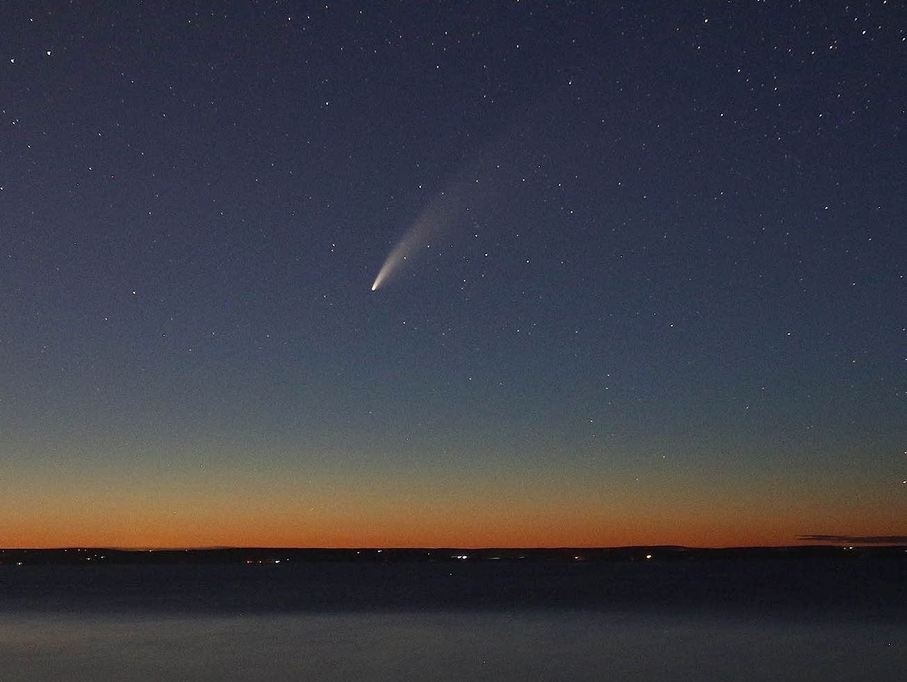 A comet is seen in the sky at dusk.