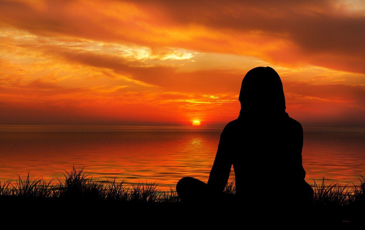 A person sitting in the grass near water.